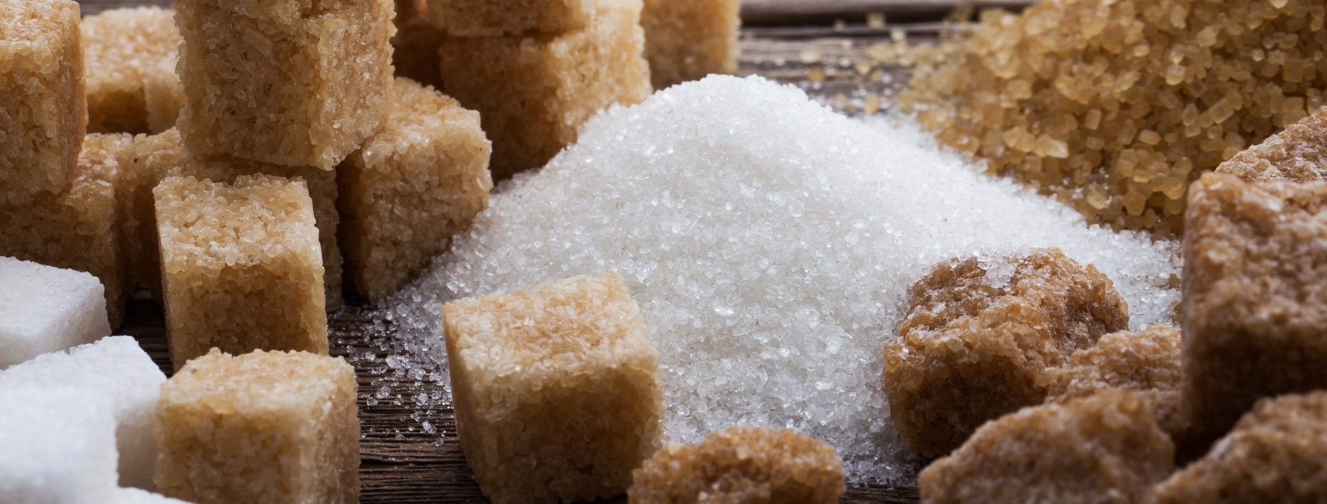 Various types of sugar, brown sugar and white on wooden background